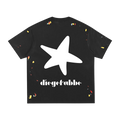 Camiseta negra getabbe vista trasera con estrella blanca grande asimétrica al centro y logo "diegetabbe" en blanco abajo, manchas de pintura multicolor rojo amarillo azul dispersas artesanalmente, hombro caído, corte holgado unisex, fondo blanco
