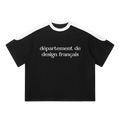 Camiseta oversized negra getabbe con texto "département de design français" en blanco al centro, panel blanco en hombros y cuello redondo en contraste, manga raglán color block, corte holgado unisex, fondo blanco