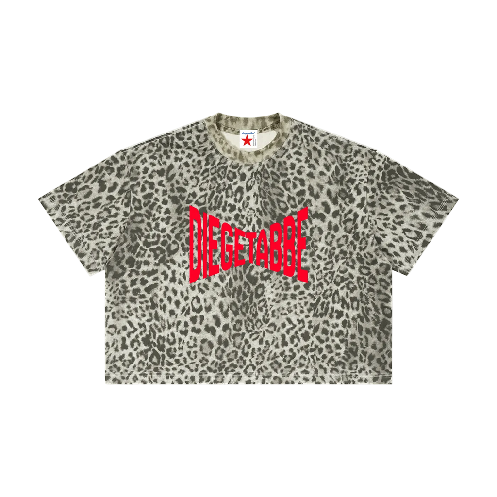 Camiseta crop getabbe con estampado leopardo gris en toda la prenda, logo "DIEGETABBE" en rojo al centro, hombro caído, corte holgado asimétrico, etiqueta con estrella roja, fondo blanco